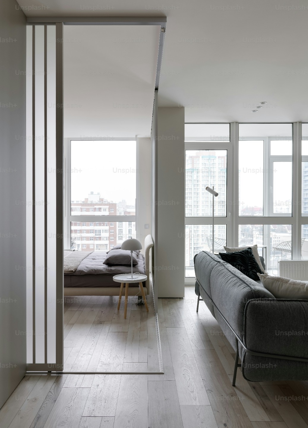 Open room showing the bed area and the living area with large window looking over a city